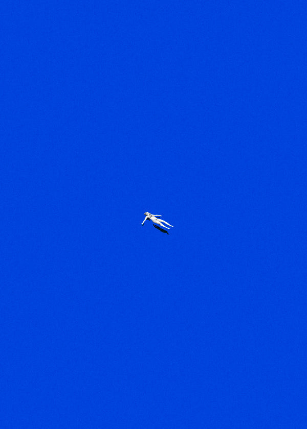 Minimalistisk plakat med svævende figur mod blå himmel