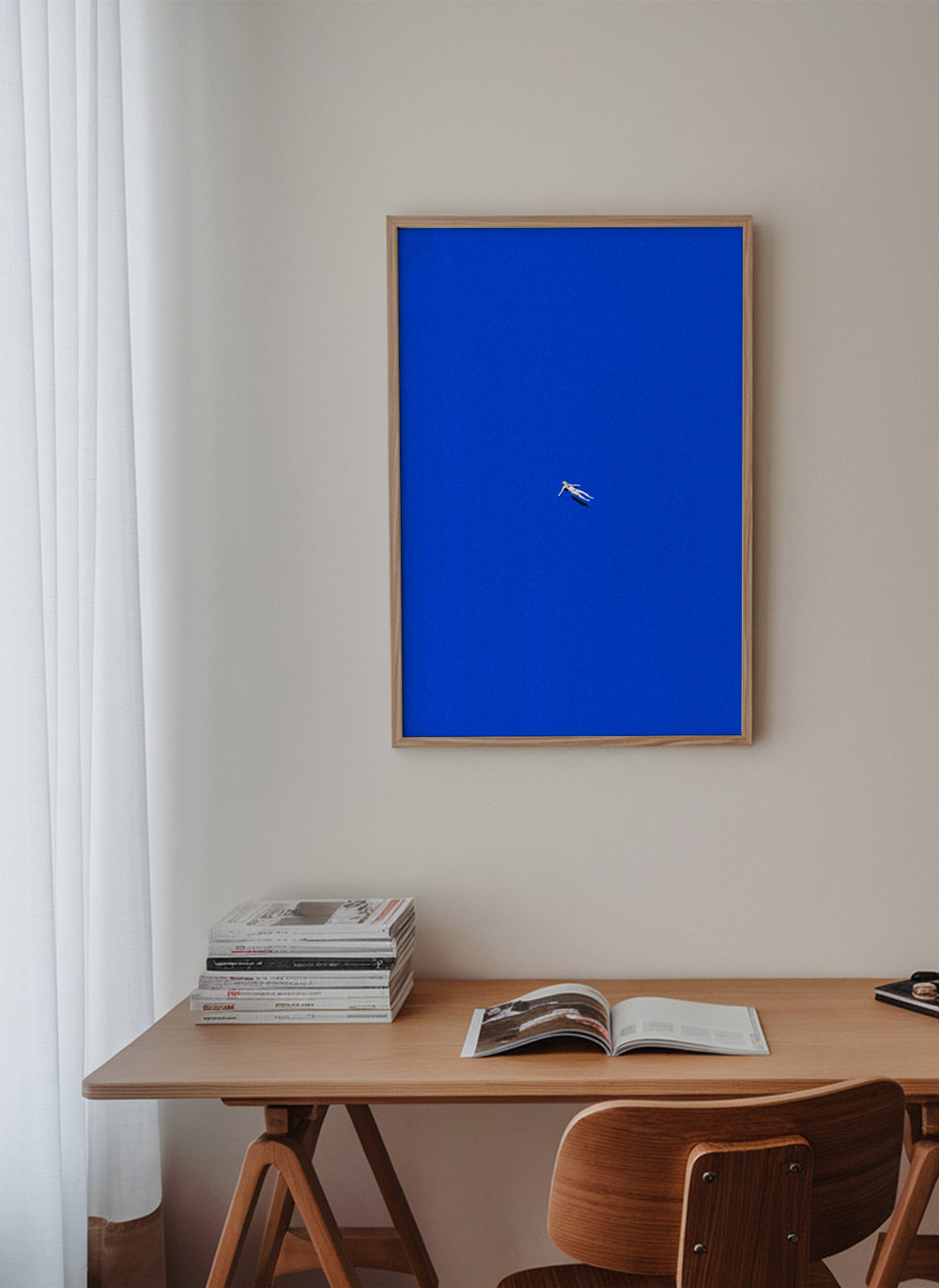Minimalistisk plakat med svævende figur mod blå himmel