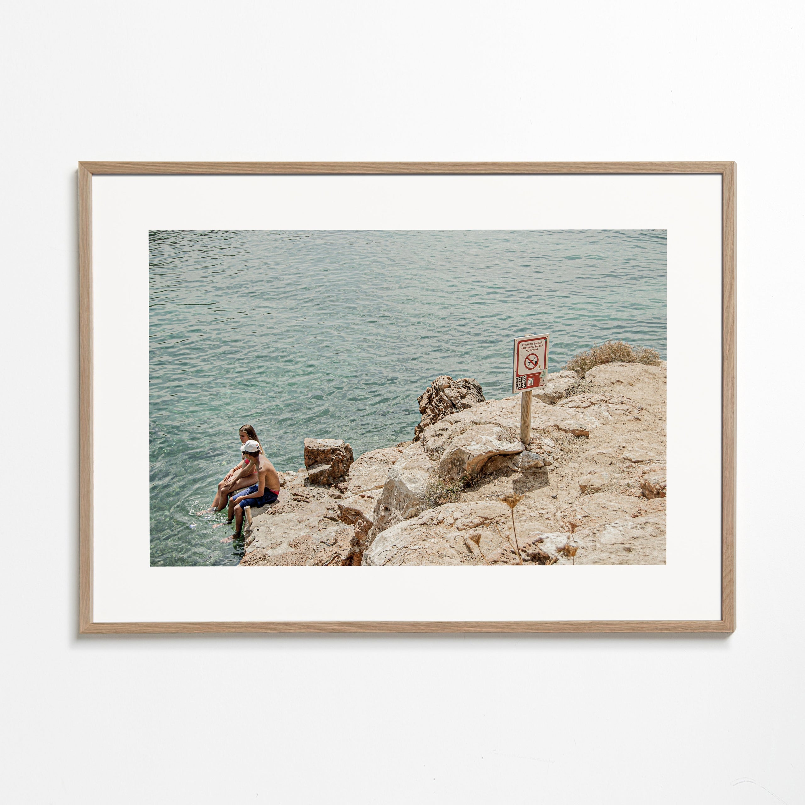 Landskabskunst: klippefyldt kyst med svømmer