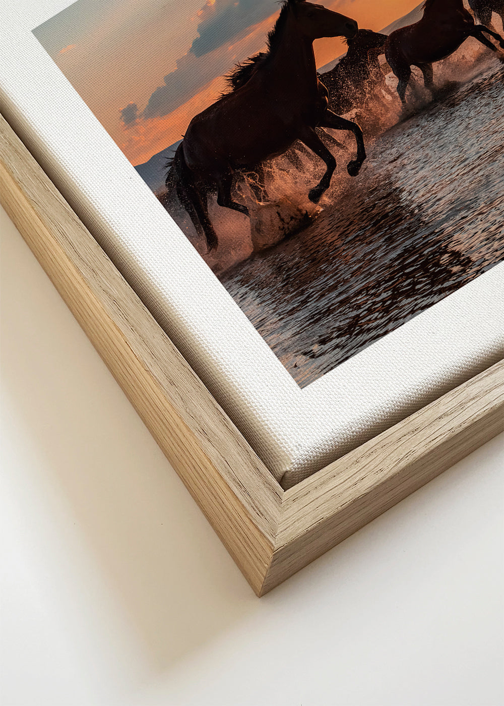 Kunstværk heste løber i vandet ved solnedgang
